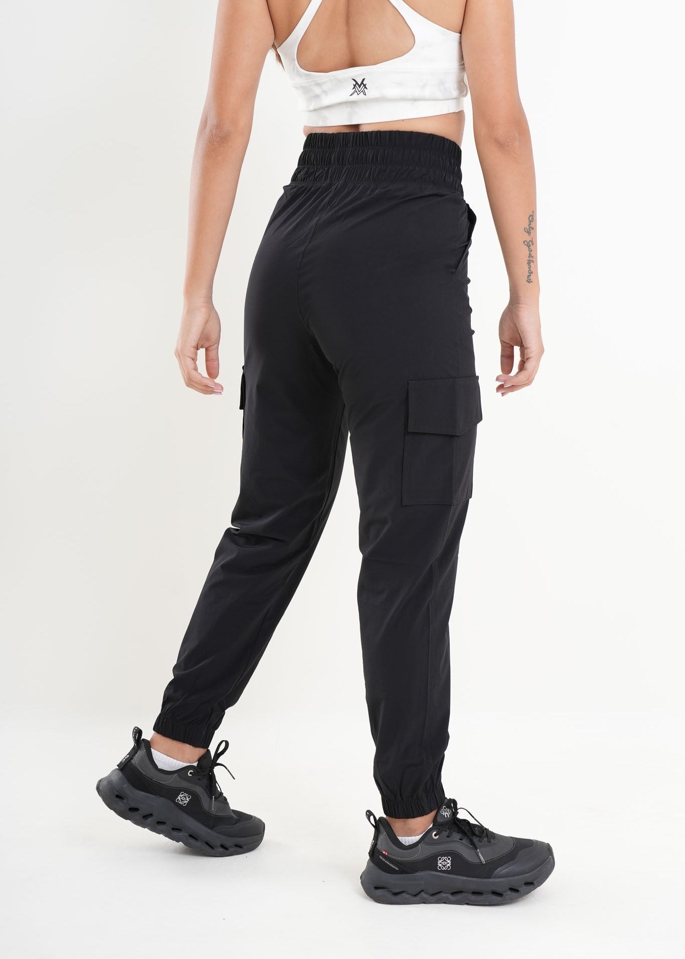 Person wearing black cargo pants and black shoes on a white background