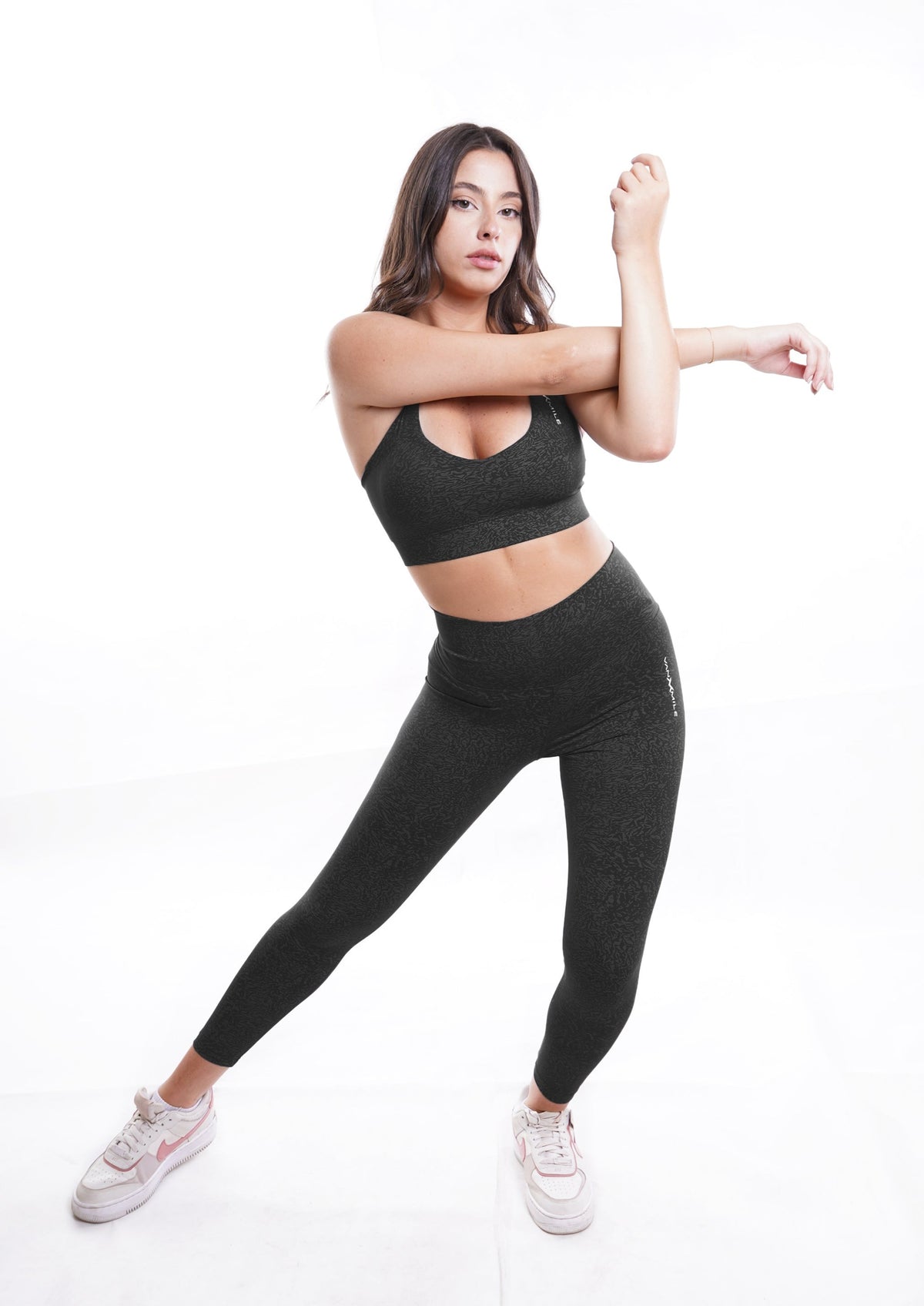 Women's VAN MILE Journey Leggings in Black – full-length stretching pose, shown with matching sports bra
