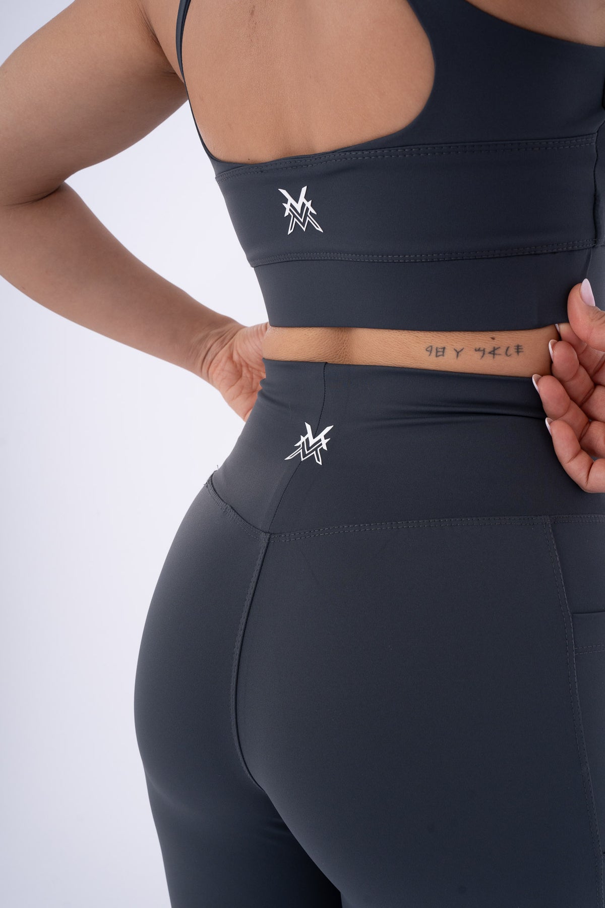 Women's VAN MILE Reborn Sports Bra in Dark Grey – back logo detail, shown with matching leggings
