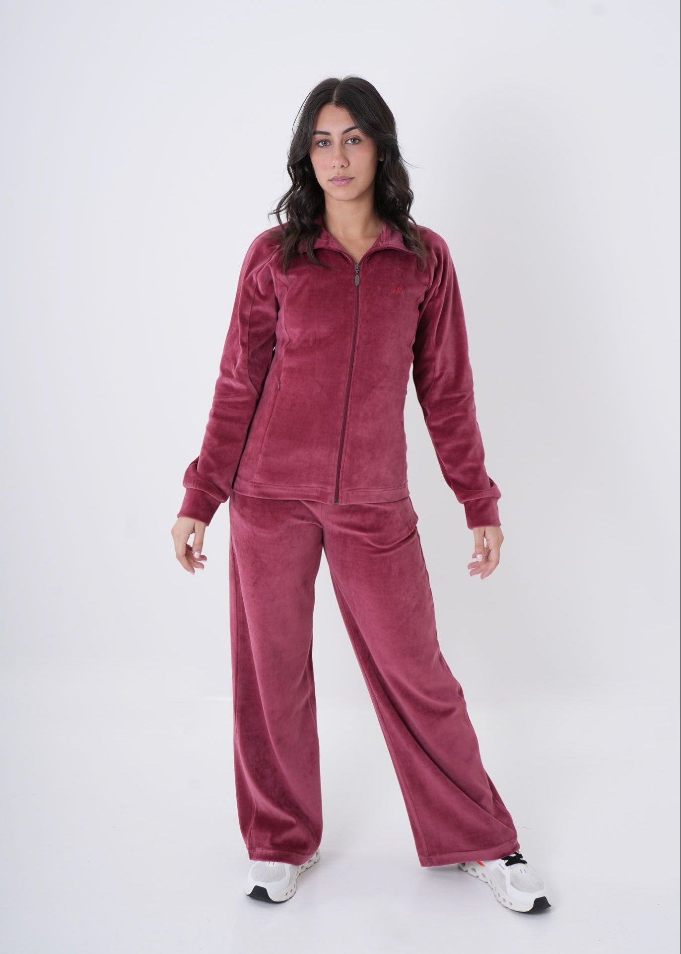 Woman wearing a burgundy velour tracksuit on a white background