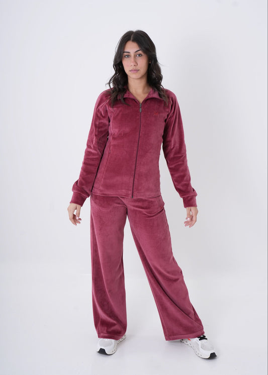 Woman wearing a burgundy velour tracksuit on a white background