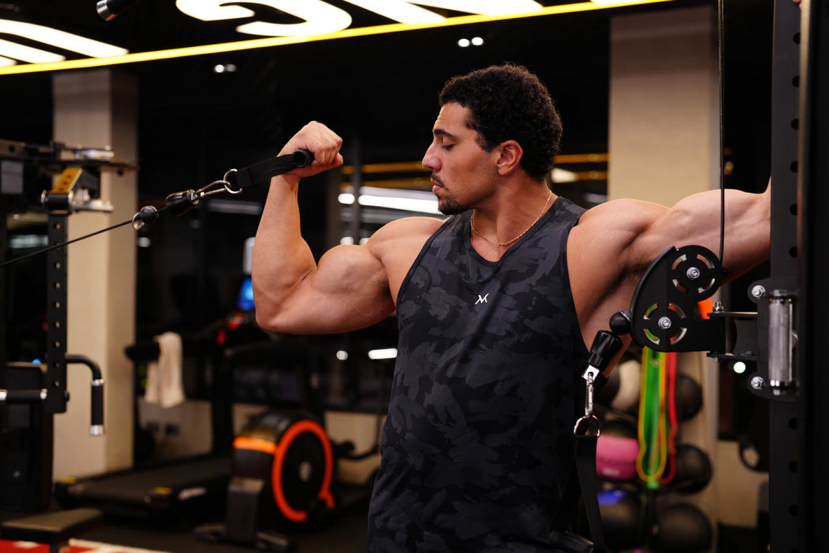 Athlete in a VAN MILE camo tank training cable curls at VAN MILE Gym